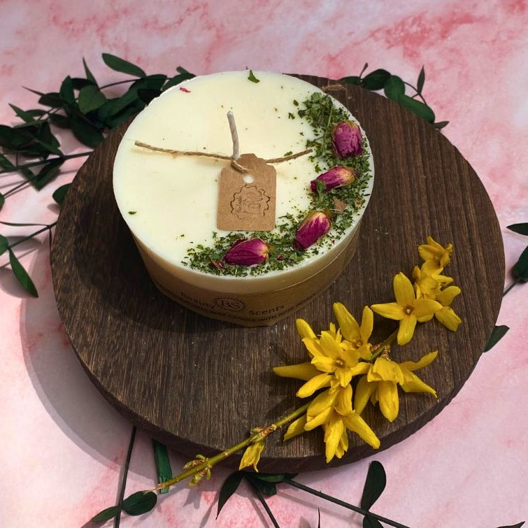 Round candles with rose buds on the wooden late with yellow flowers