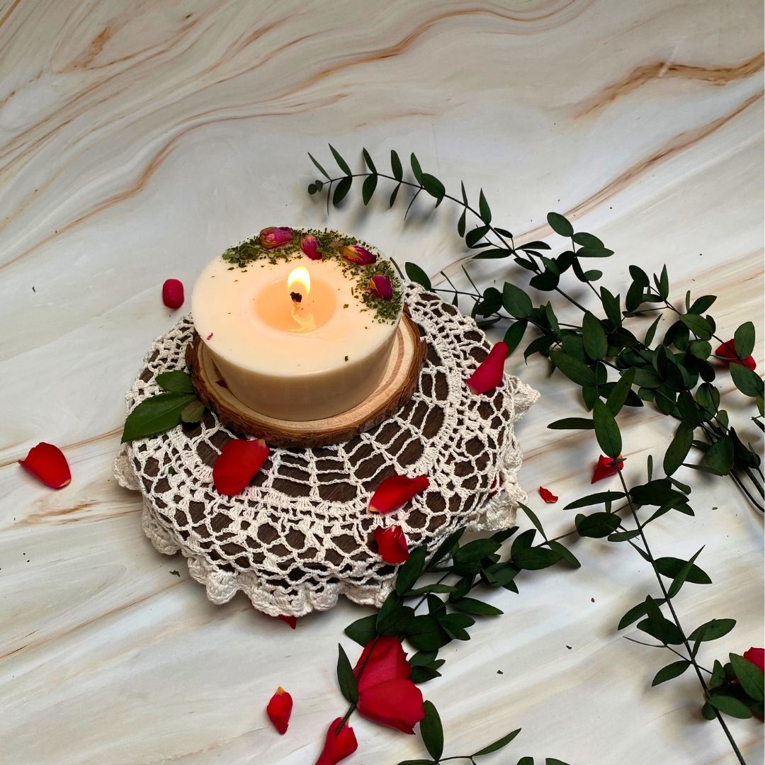 Burning medium pillar candle decorated with real rose buds, handmade by Beauty Scents, rustic country-style setting