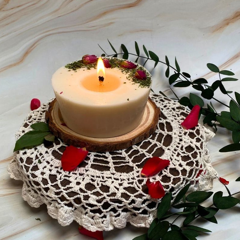 Candle on a wooden stand with decorative elements on a marble surface