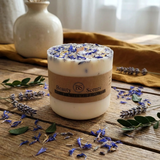 Beauty Scents handmade candle with wildflowers and kraft label, styled with green leaves and petals beside a vase on wood.