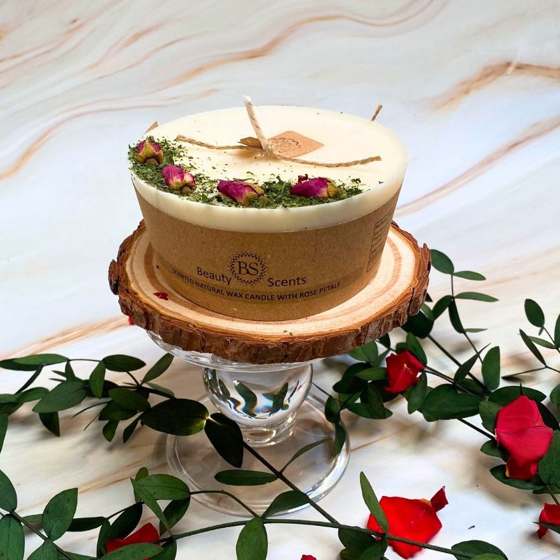 Wax candle with natural elements on a wooden stand with flowers and leaves.