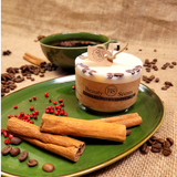Beauty Scents small coffee candle with embedded coffee beans on green ceramic plate decorated with cinnamon sticks and red berries on natural burlap background