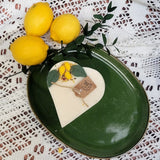 Green plate with a heart-shaped candle and lemons on a lace tablecloth