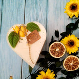 Heart-shaped candle with yellow flowers and a tag on a blue wooden background