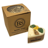 Heart-shaped candle with natural elements and a cardboard box labeled 'Beauty Scents' on a white background.