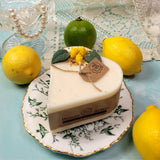 Heart-shaped candle with 'Beauty Scents' branding on a decorative plate with lemons and limes.