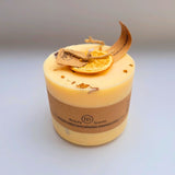 Large handmade scented candle by Beauty Scents, decorated with a dried orange slice and cinnamon stick pieces, shown against a plain light background.