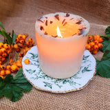 Candle on a decorative plate with berries and leaves on a burlap background