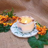 Candle on a decorative plate with berries and leaves on a textured fabric background