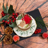 Close-up view of small Winter Poinsettia candle showing detailed red flower and green leaf decoration