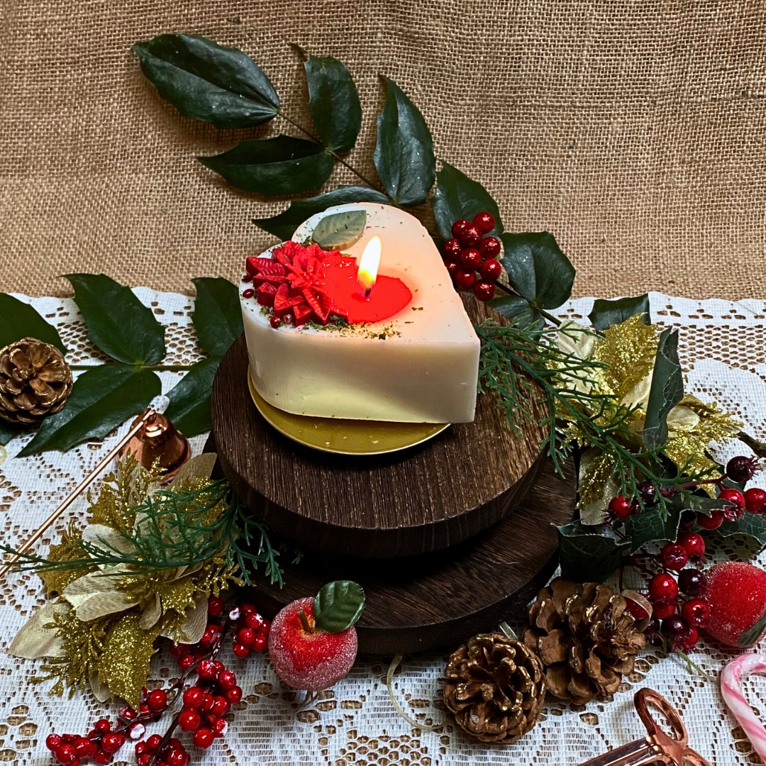 Small heart Winter Poinsettia candle top view showing white wax with festive botanical decoration
