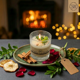 Beauty Scents Candle With Apples in a glass jar  on a plate with dried apple slicescinnamon sticks and rose petals, fireplace in the background