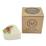 Heart-shaped candle with wax cherries and green leafs on a white background next to a cardboard box labeled 'Beauty Scents'.