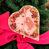Small heart-shaped mulled wine scented candle decorated with star anise and red berries on white soy wax background
