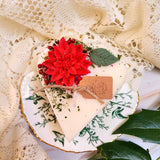 Small heart-shaped hollyberry scented candle decorated with winter poinsettia flowers on white soy wax background