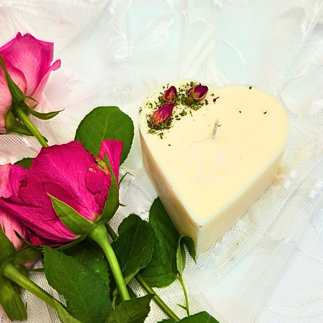 Heart-shaped candle with rose petals on a white fabric background