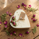 Heart-shaped candle with dried flowers on a wooden surface, featuring Beauty Scents Candles branding.