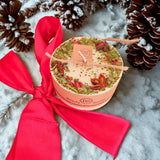 Small heart-shaped mulled wine scented candle decorated with star anise and red berries on white background