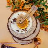 Small heart-shaped orange and cinnamon scented candle decorated with shredded cinnamon sticks on white background