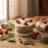 Small Beauty Scents raspberry candle with raspberry wax melts and green botanicals on top, displayed on a rustic wooden table with dried leaves, twine, and fresh raspberries, square image.