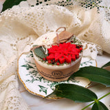 Small heart-shaped hollyberry scented candle decorated with winter poinsettia flowers on white background
