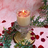 Beauty Scents rose petals candle burning on glass plate with fresh roses and eucalyptus on white lace
