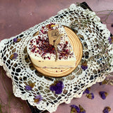 Beauty Scents small heart rose petals candle with dried botanicals on wooden plate surrounded by vintage white lace and purple wildflowers