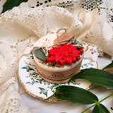 Small hollyberry scented candle decorated with winter poinsettia flowers on white soy wax background