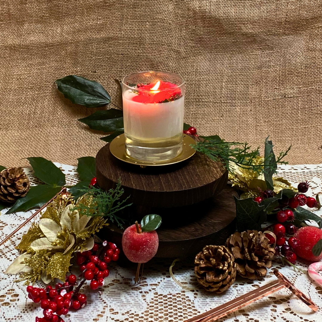 Small glass Winter Poinsettia candle burning shot showing flame and festive decoration in glass container