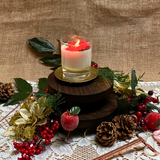 Small glass Winter Poinsettia candle burning shot showing flame and festive decoration in glass container