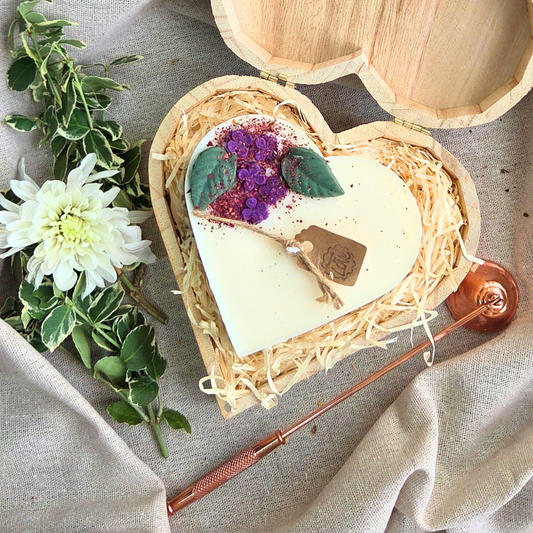 Large heart-shaped candle with lilac decorations in a wooden heart gift box