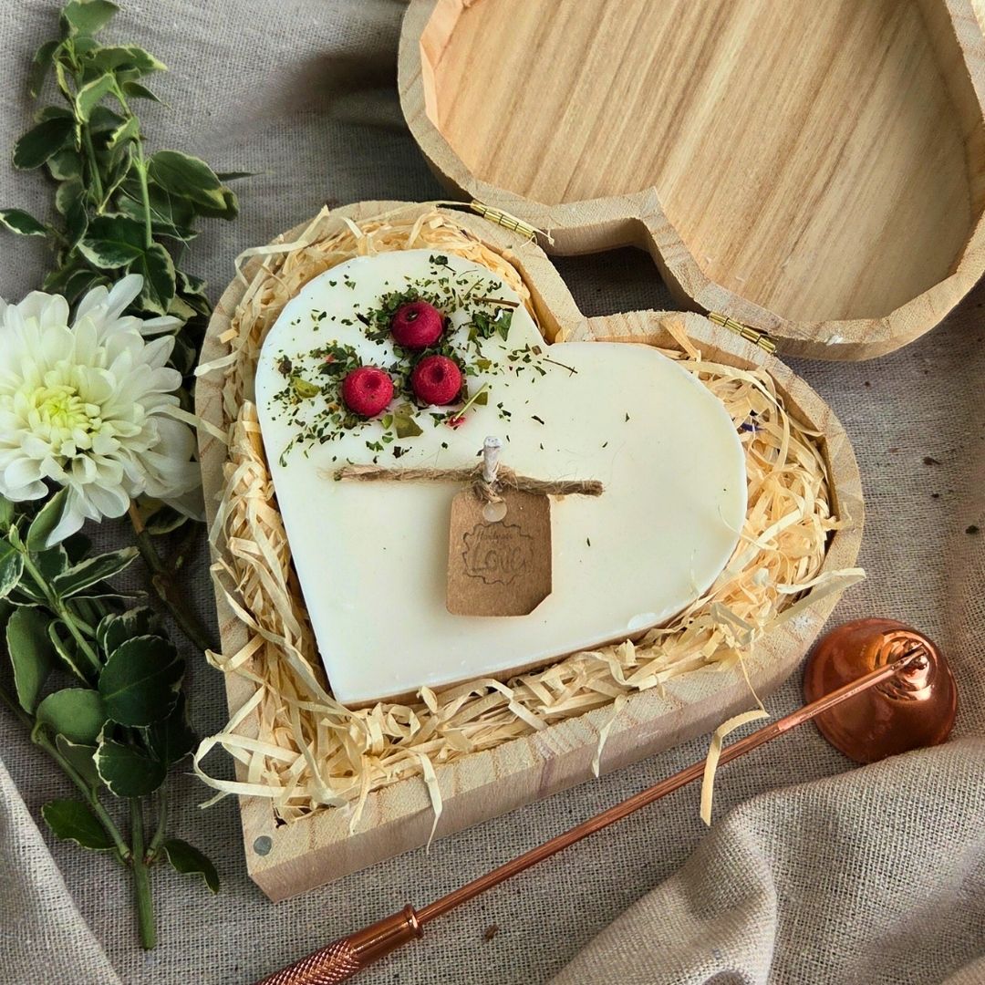 Large heart-shaped candle with red berry decorations in a wooden heart gift box