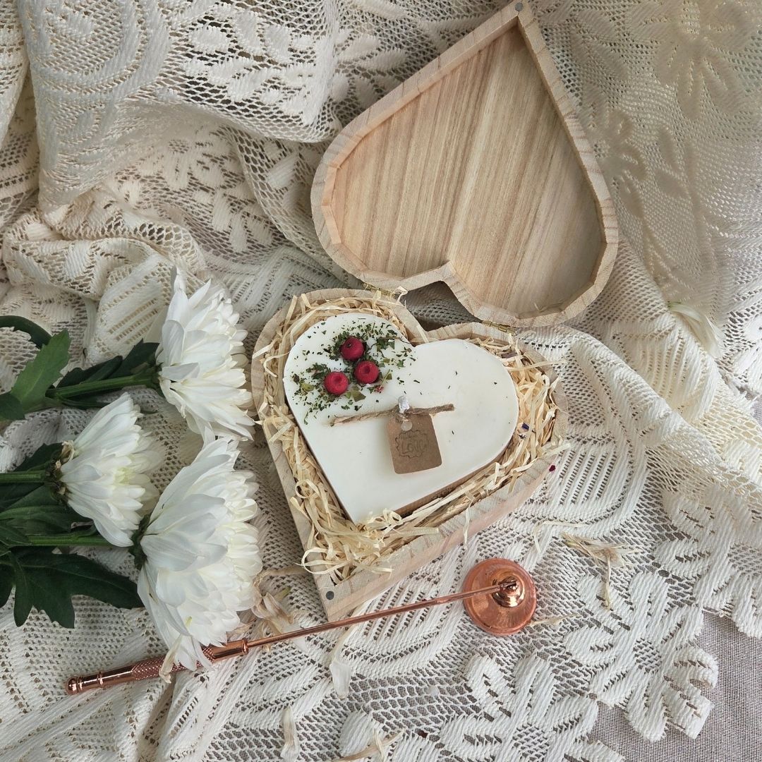 Handmade heart candle decorated with red berries in rustic wooden box