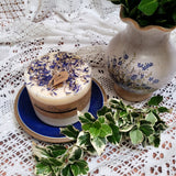 Large Wild Flowers soy candle 700g with blue cornflowers decoration on blue ceramic plate, styled with white lace doilies and fresh foliage - rustic lifestyle photography