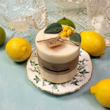 Beauty Scents medium lemon candle with botanicals on vintage botanical plate with fresh lemons and crystal glass