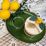 Medium lemon scented candle with botanicals on vintage green serving set with fresh lemons and white lace
