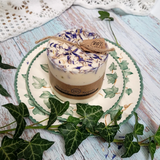 Candle with floral design on top, placed on a decorative plate with ivy leaves