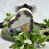 Decorative heart-shaped candle with flowers and berries on a textured white surface