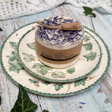Small handmade wild flowers soy candle with dried blue cornflowers and rustic kraft gift tag styled with natural ivy on floral plate